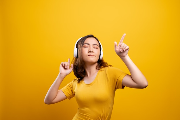 Mulher com fones de ouvido, ouvindo música no fundo amarelo isolado