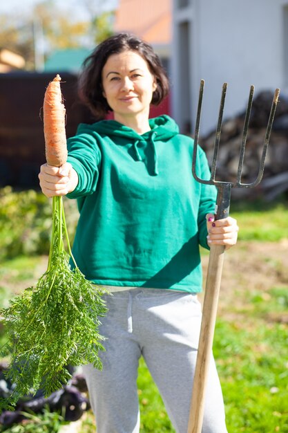 Mulher com forcado e cenoura no jardim