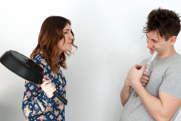 Foto mulher com frigideira repreendendo homem bêbado com uma garrafa de vodka na mão humor em 8 de março dia internacional da mulher