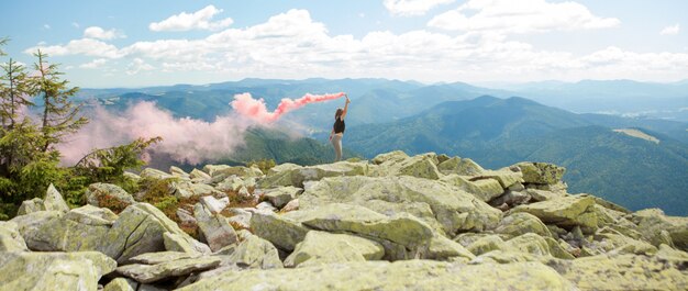 Mulher com fumaça vermelha em uma montanha