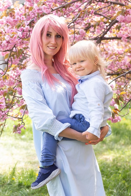 Mulher com garotinho perto de árvore florescendo de sakura rosa Conceito de primavera