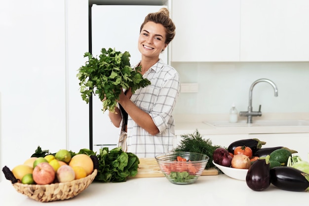 Mulher com grande monte de coentro verde durante o cozimento na cozinha