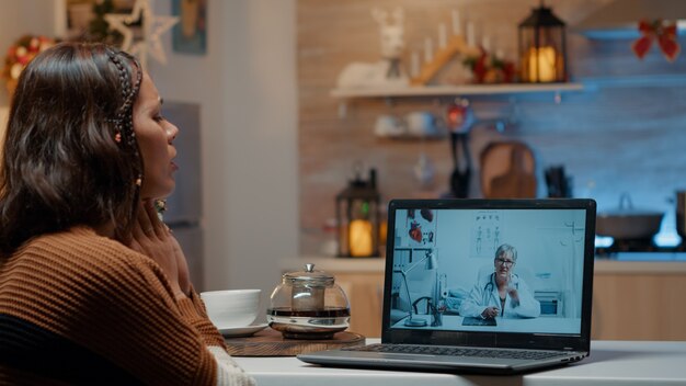 Mulher com gripe usando telemedicina no laptop em casa