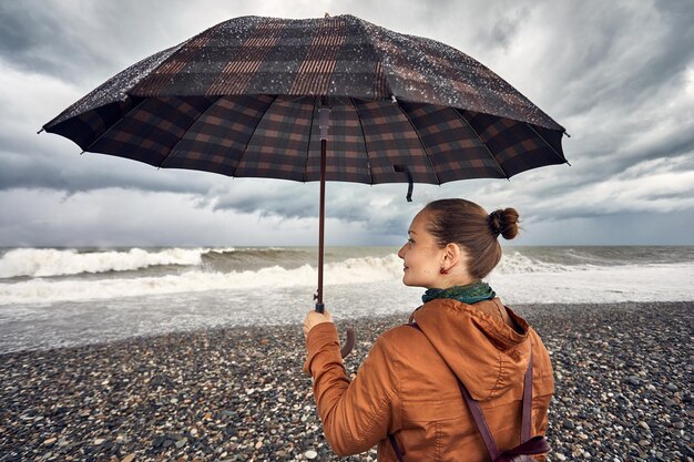 Mulher com guarda-chuva perto do mar tempestuoso