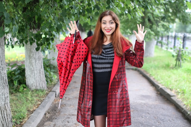 Mulher com guarda-chuva vermelho na árvore da rua