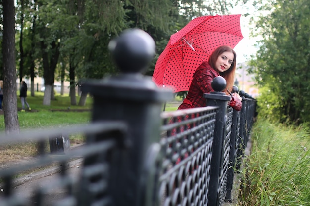 Mulher com guarda-chuva vermelho na árvore da rua