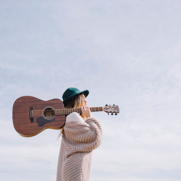 Foto mulher com guitarra no fundo do céu