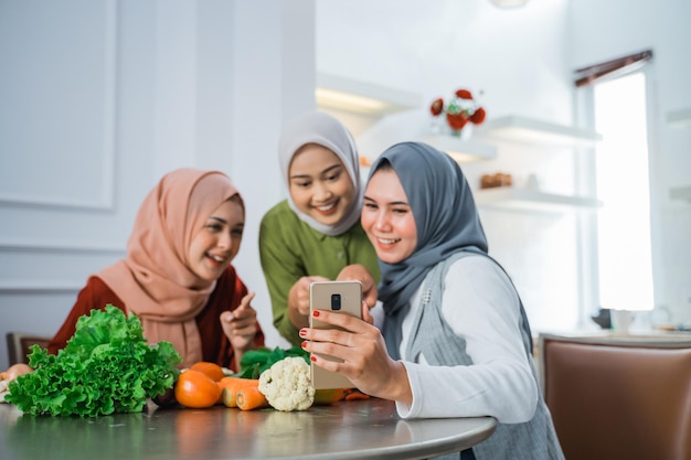 Mulher com hijab cozinhando na cozinha enquanto olha para a internet