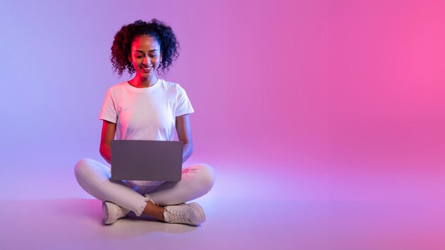 Mulher com laptop sentada de pernas cruzadas