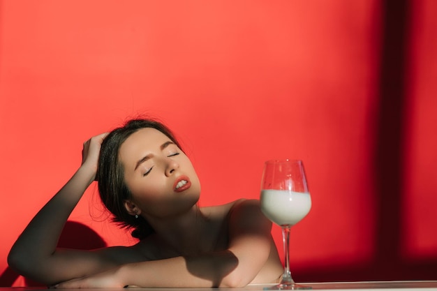 Mulher com leite de vidro sobre fundo vermelho. Foto criativa