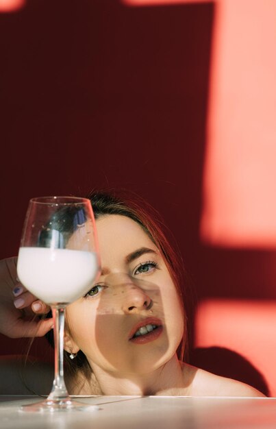 Foto mulher com leite de vidro sobre fundo vermelho. foto criativa