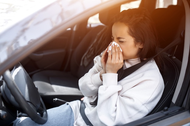 Mulher com lenço. menina doente tem corrimento nasal. modelo feminino faz uma cura para o resfriado comum no carro