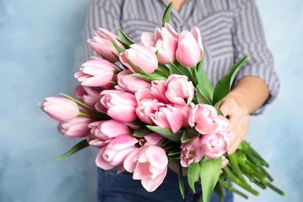 Mulher com lindas tulipas de primavera rosa sobre fundo azul claro closeup
