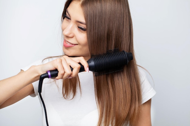 Mulher com lindos cabelos longos e lisos usando alisador de cabelo