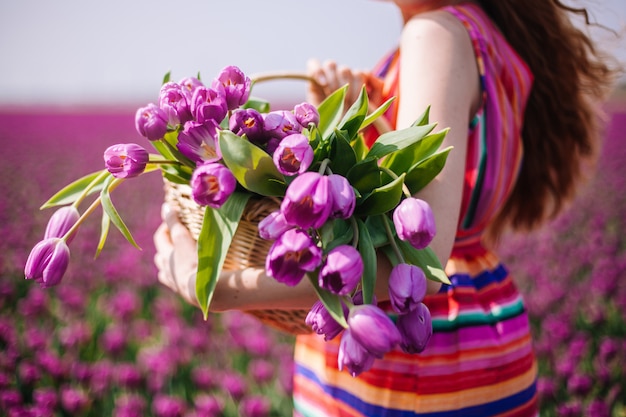 Mulher, com, longo, cabelo vermelho, desgastar, um, vestido listrado, segurando, um, cesta, com, buquê, de, roxo, tulips, flores