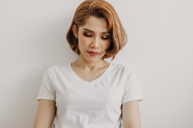 Foto mulher com look descolado de camiseta branca e jeans relaxando no quarto do apartamento