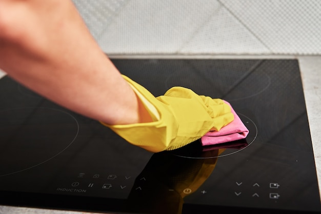 Foto mulher com luvas de borracha limpando fogão de indução