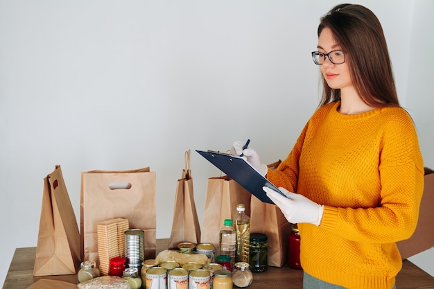 Mulher com luvas médicas embalando comida para doação