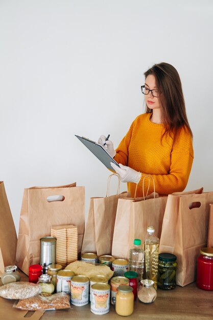 Mulher com luvas médicas embalando comida para doação