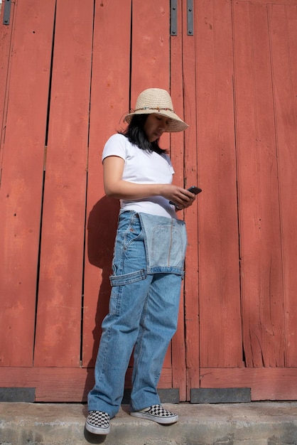 Mulher com macacão jeans olhando para o smartphone