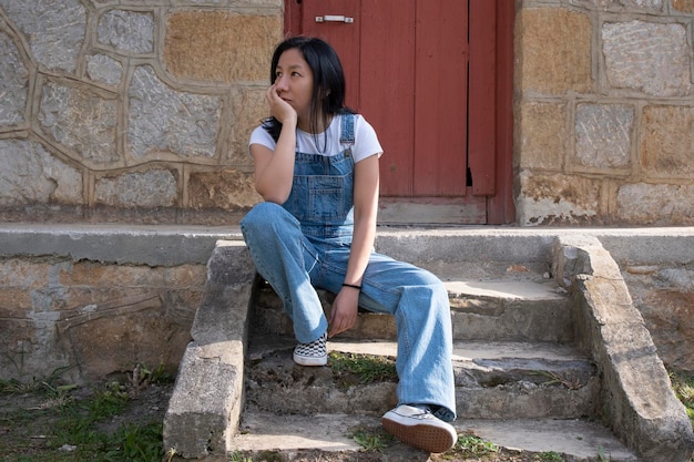 Mulher com macacão jeans sentado em uma escada