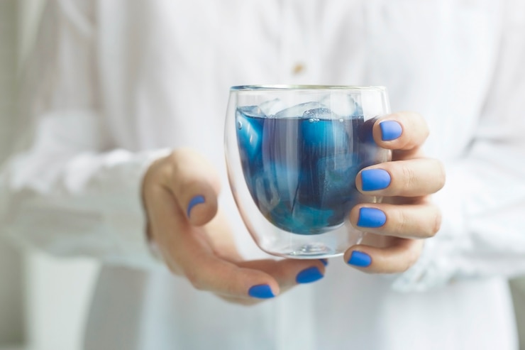 Foto mulher com manicure azul clássico segura um copo de chá matcha azul