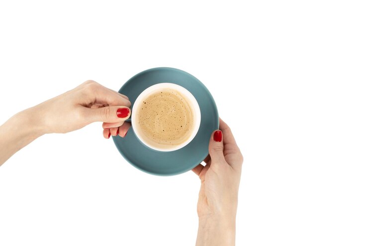 Foto mulher com manicure vermelha segurando uma xícara de café azul isolada em um fundo branco com traçado de recorte