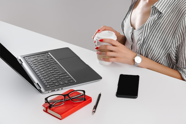 Mulher com manicure vermelha trabalhando com laptop na mesa branca senhora trabalha em casa