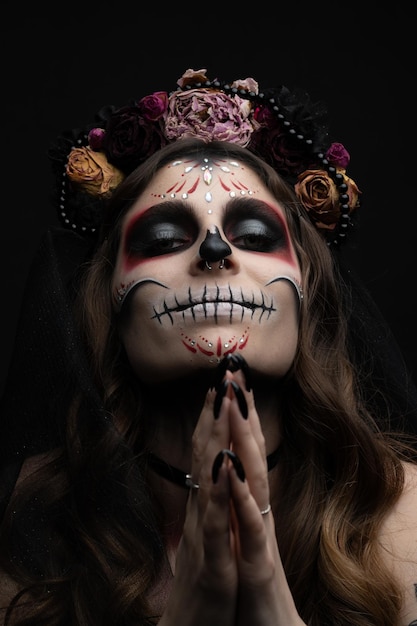 Mulher com maquiagem artística assustadora e flores frescas na cabeça em pé preparada para festa de halloween
