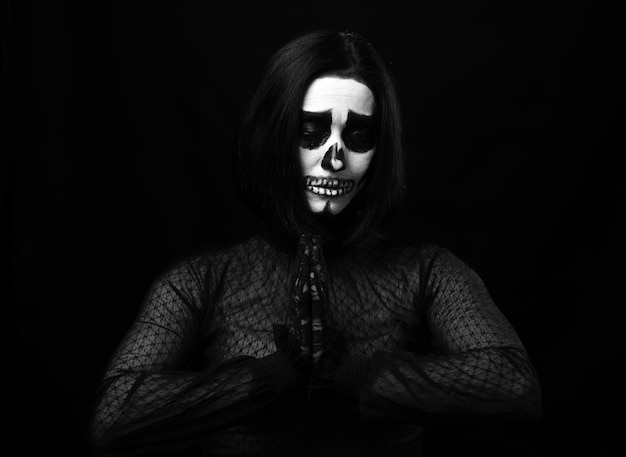 Mulher com maquiagem de esqueleto em pose de oração