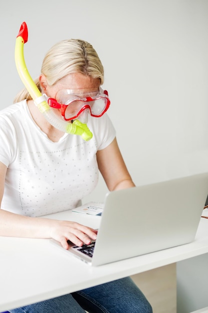 Mulher com máscara de mergulho buscando ofertas online para suas férias na praia mulher sonhando com mar no local de trabalho