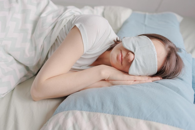 Mulher com máscara de sono está deitada na cama e dormindo uma mulher europeia feliz com saúde mental e