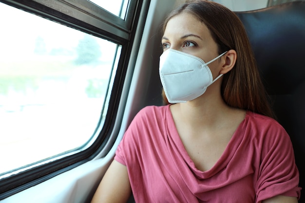 Mulher com máscara facial KN95 FFP2 olhando pela janela do trem