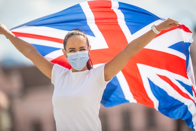 Mulher com máscara facial segura uma bandeira do reino unido durante a campanha de permanência forte.