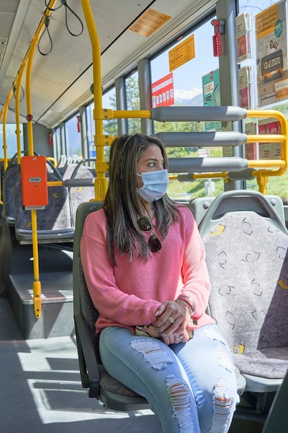 Mulher com máscara facial viajando pela cidade de ônibus