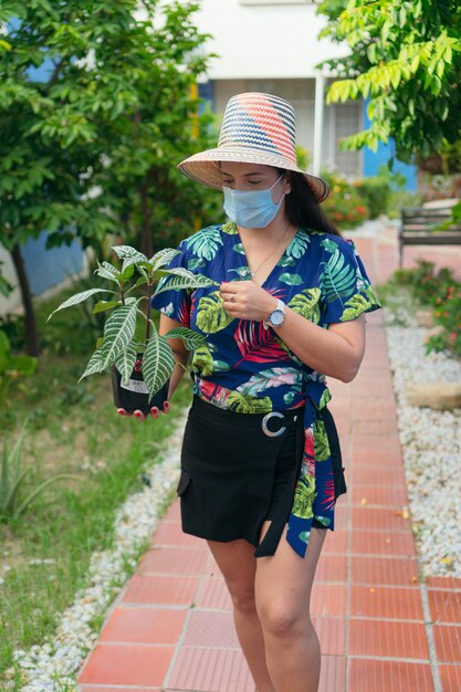 Mulher com máscara protetora, escolhendo plantas em casa. Conceito de selva urbana