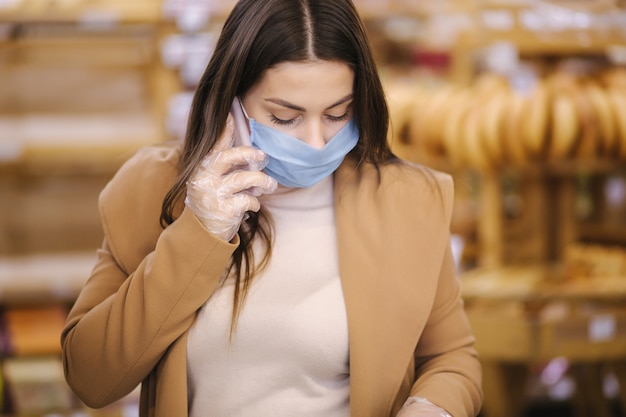 Mulher com máscara protetora falando ao telefone no supermercado