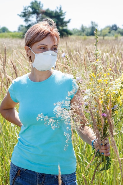 Mulher com máscara protetora segurando buquê de flores silvestres e tentando lutar contra alergias ao pólen.