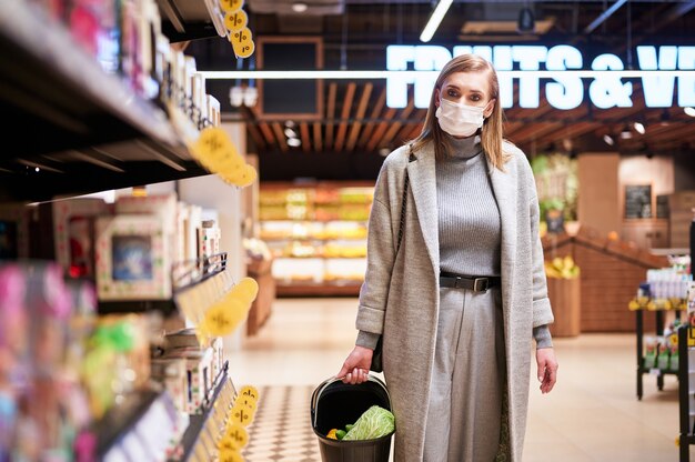 Mulher com máscaras médicas faz compras em um supermercado durante a pandemia de vírus