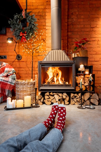 Mulher com meias de Natal junto à lareira em casa. O conceito de conforto durante as férias de inverno e ano novo
