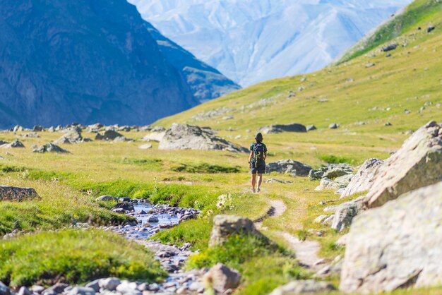 Mulher com mochila caminhadas na montanha, geleira cênica e dramática paisagem verão fitness bem-estar vista traseira, o conceito de liberdade