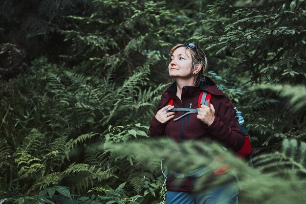 Foto mulher com mochila caminhando na floresta passando ativamente as férias de verão perto da natureza