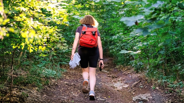 Mulher com mochila de caminhada em uma trilha em uma floresta