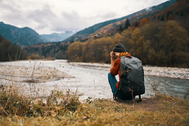 Mulher com mochila montanhas paisagem nuvens grama amarela modelo de viagem foto de alta qualidade