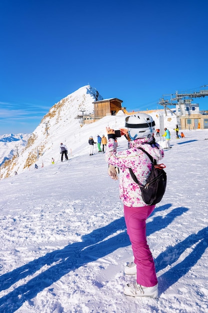 Mulher com mochila tirando foto na câmera do celular de Hintertux Glacier no Tirol em Mayrhofen no vale de Zillertal, Áustria, Alpes de inverno. Moça na estância de esqui de Hintertuxer Gletscher nas montanhas
