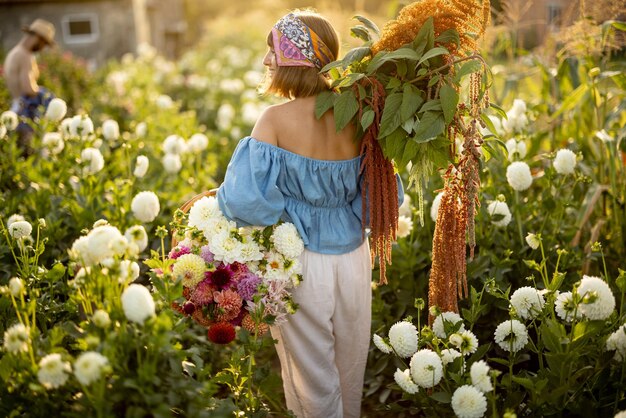 Mulher com muitas flores na fazenda dália ao ar livre