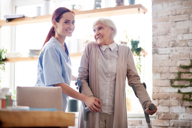 Mulher com muletas sorrindo enquanto conversava com o cuidador