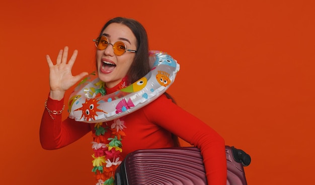 Foto mulher com óculos de sol hawaiian lei caminhando com bolsa de bagagem anel de natação viagem de férias