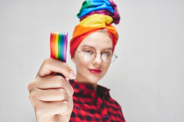 mulher com óculos de turbante arco-íris e camisa vermelha mostra o conceito LGBTQ dedo médio e língua