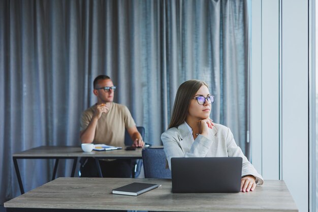 Mulher com óculos na mesa enquanto trabalhava com colegas no escritório conceito de empresários bem sucedidos modernos homem e mulher sentados em mesas de madeira